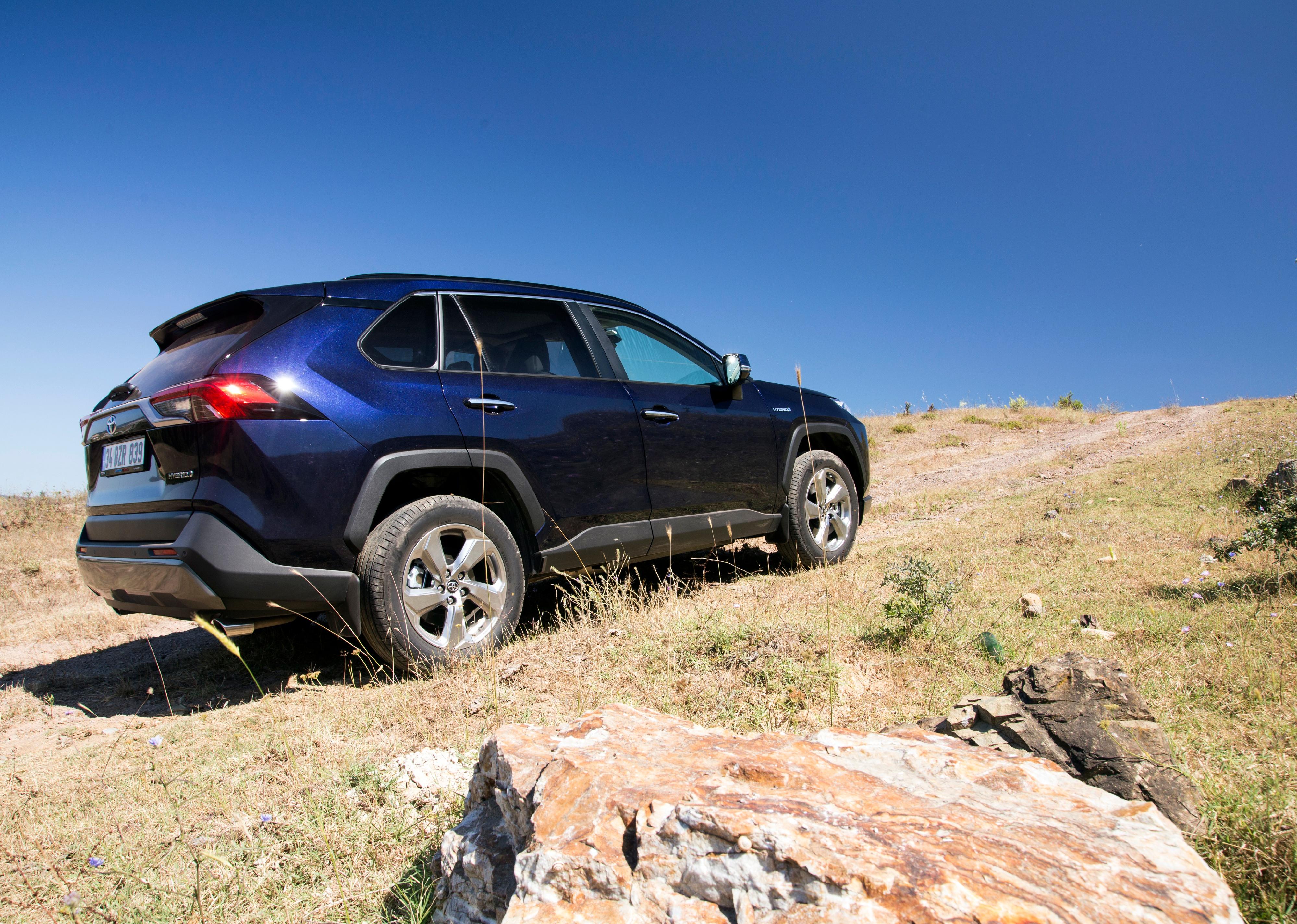 A blue Toyota RAV4 driving up a dirt hill.
