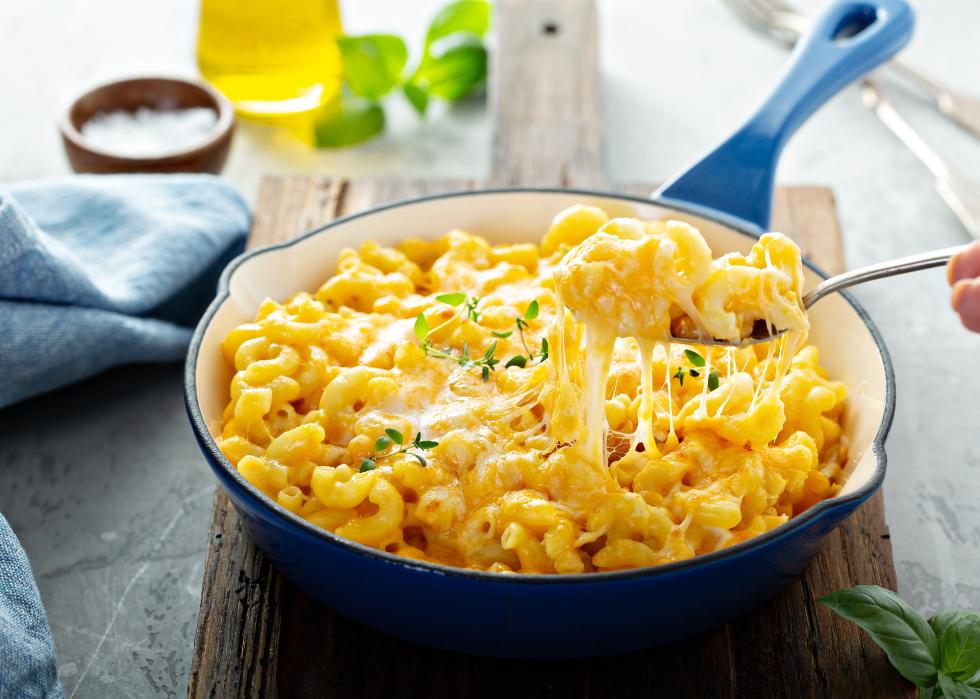 Baked mac and cheese in a cast iron pan on a wooden serving board. 
