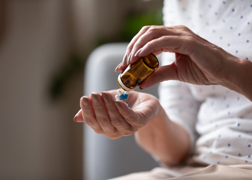 Close up mature woman taking out pills from bottle