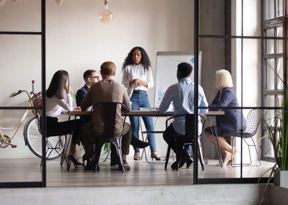 Female standing and speaking to business group at table