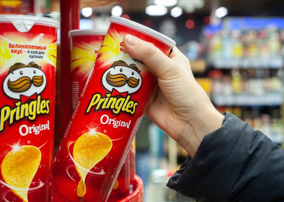 Hand hold a new tube of Pringles Potato Chips.