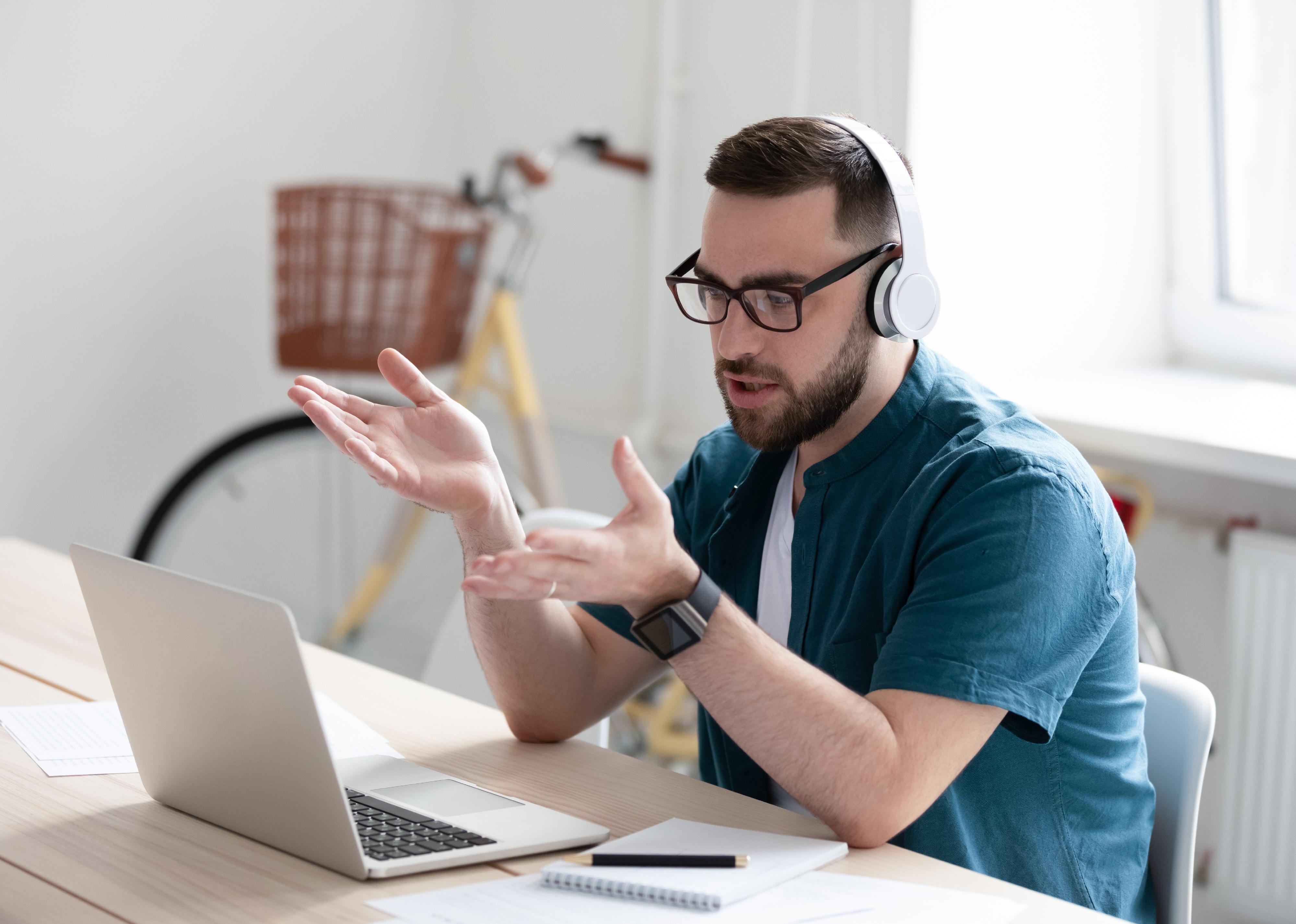 Focused young man in eyewear wearing headphones on a video call.