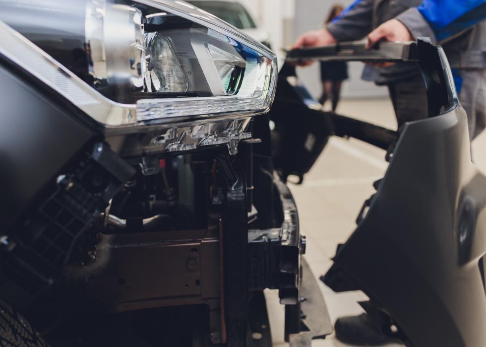 Man replacing bumper on a car.