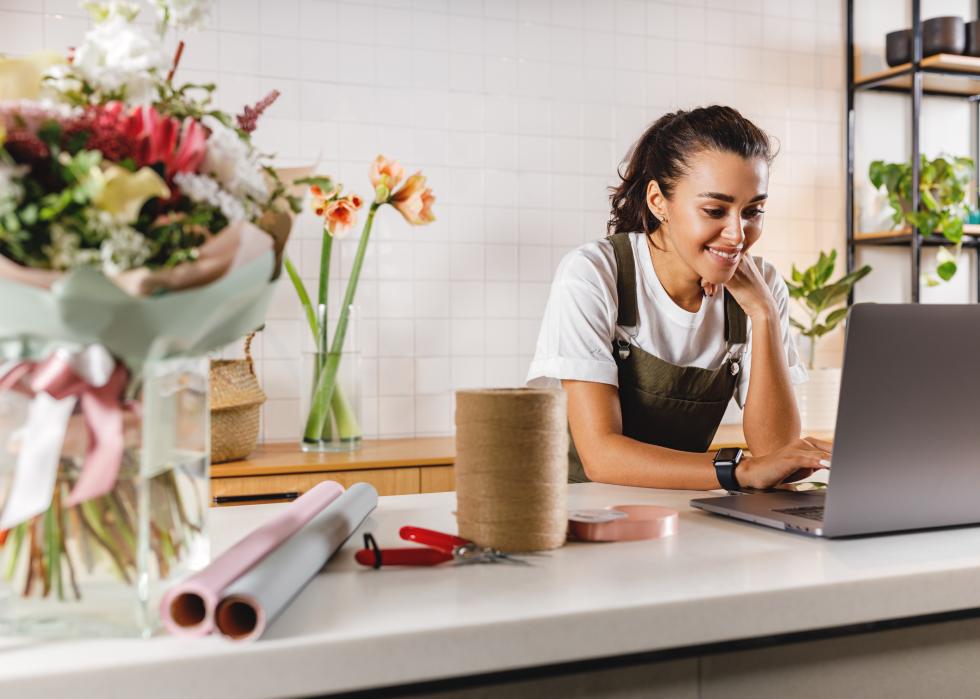 Smiling flower shop owner using laptop computer