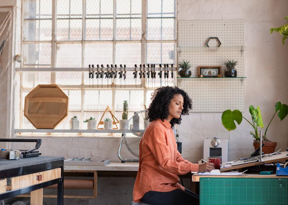 Young woman working on a laptop and writing notes