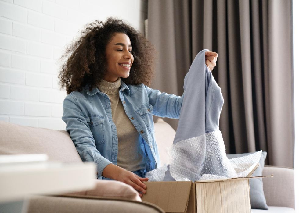 Woman pulls out a sweater from a cardboard box