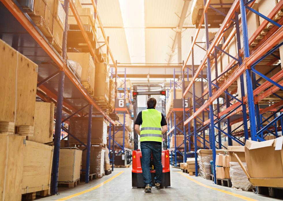 Storehouse employee in uniform walking in modern automatic warehouse.