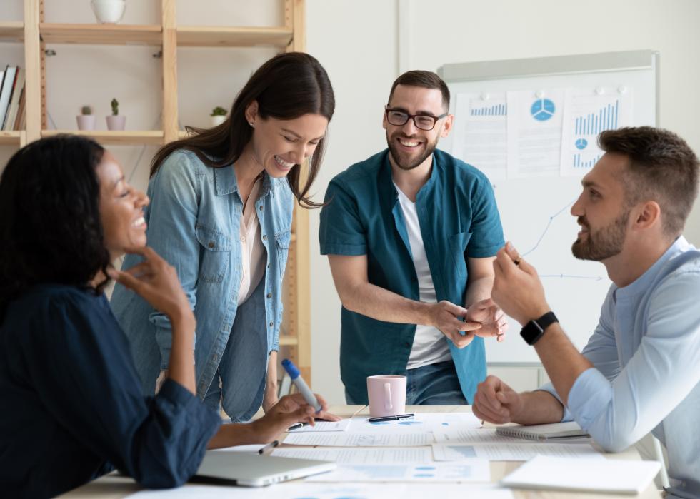 Coworkers smile and talk together in a meeting room