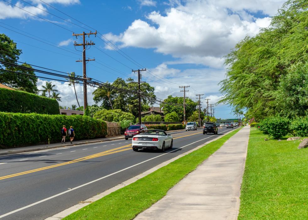 Roadway with cars and people walking.