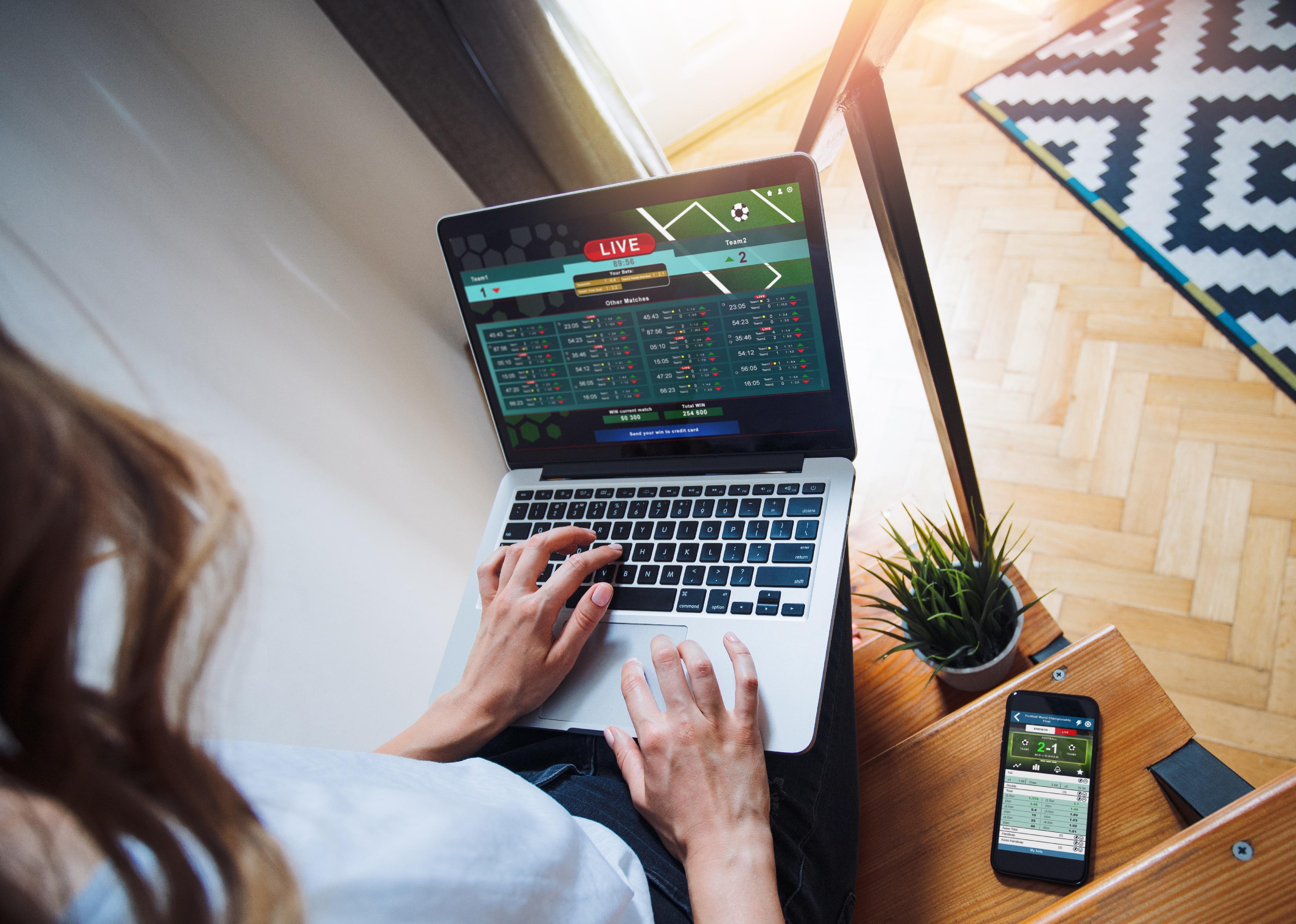 Woman using a laptop tosport bets online on a bookmaker's website.
