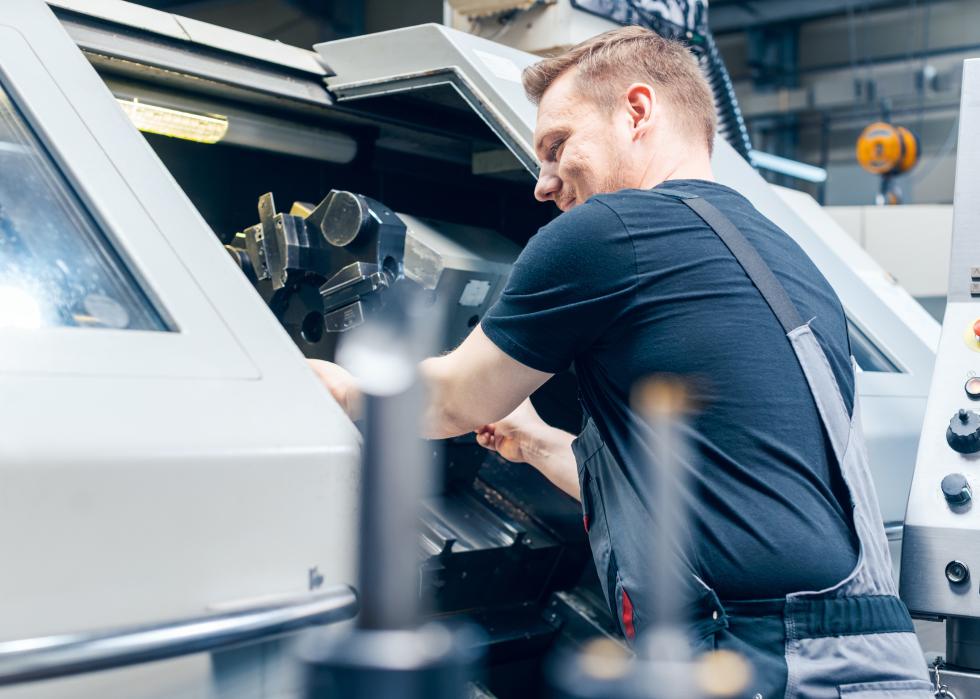 Male factory worker changing tool setup of lathe machine