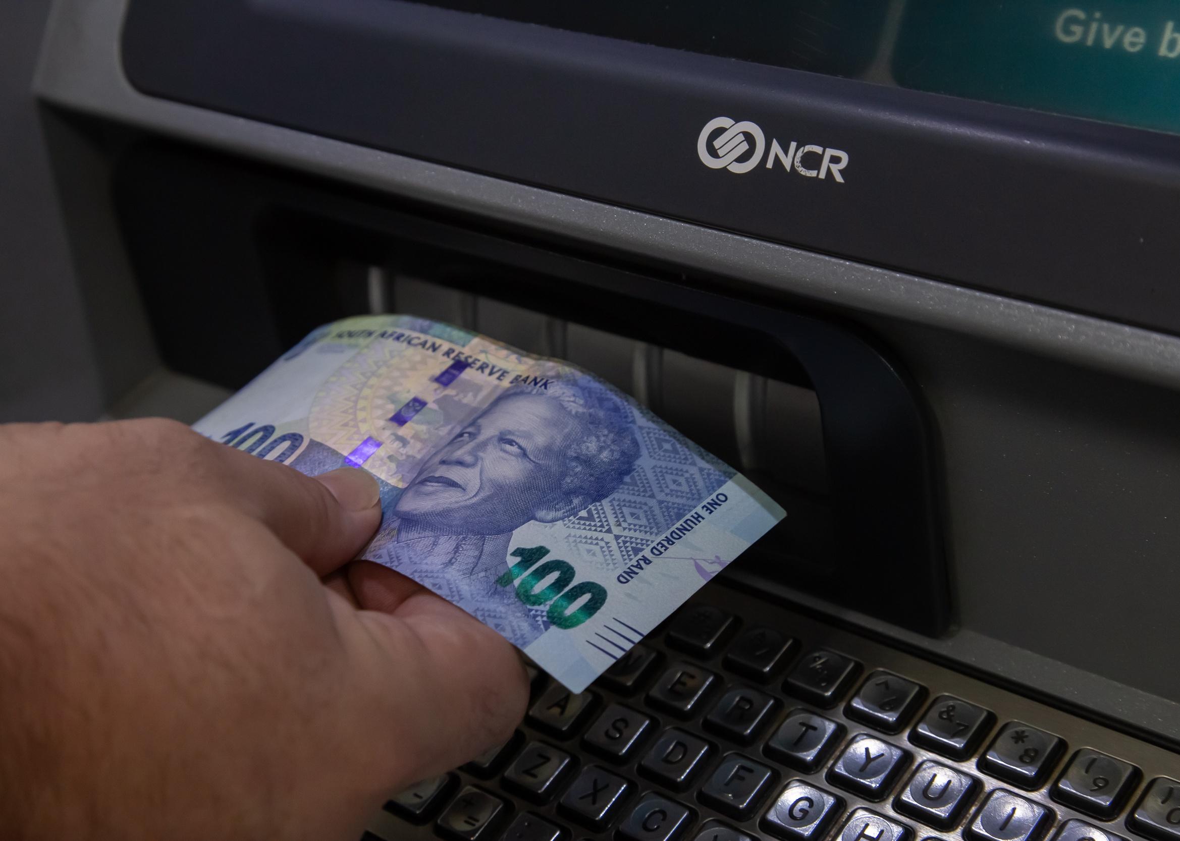 Close-up of hands getting cash out of ATM