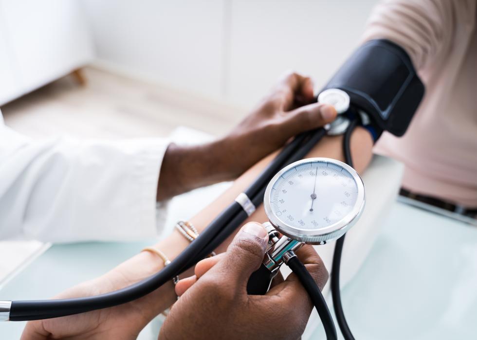 Close-up of a doctor measuring a patient's blood pressure with a stethoscope.