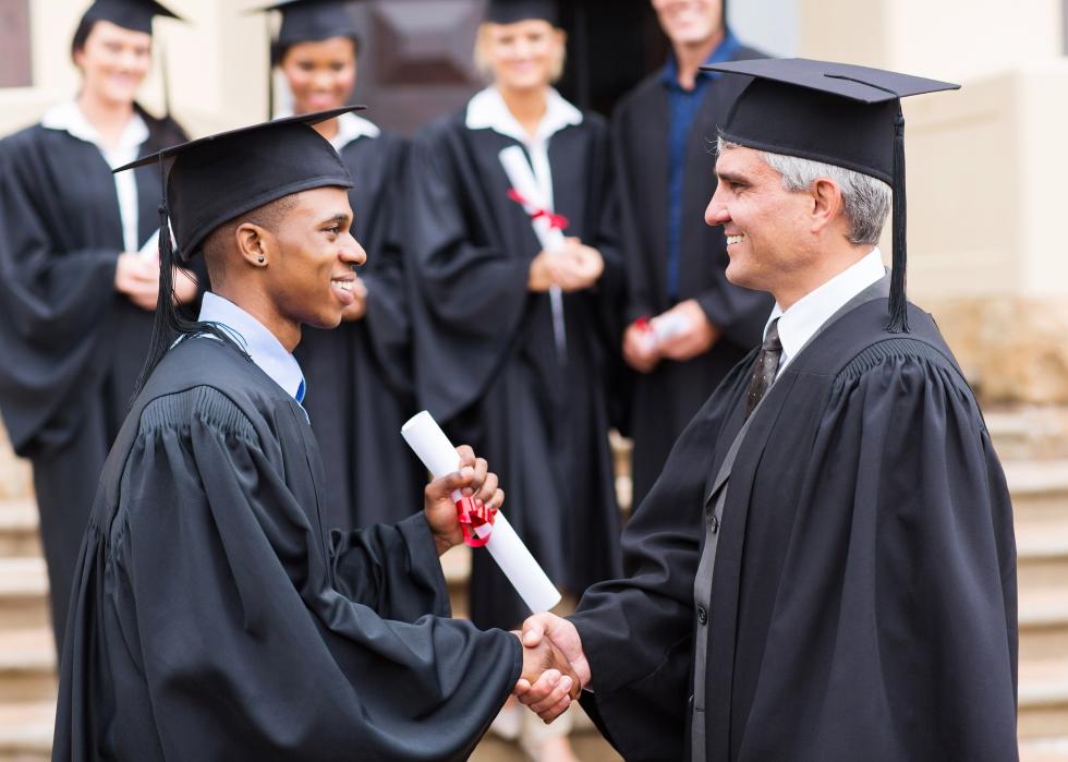 Happy male graduate handshaking with dean.
