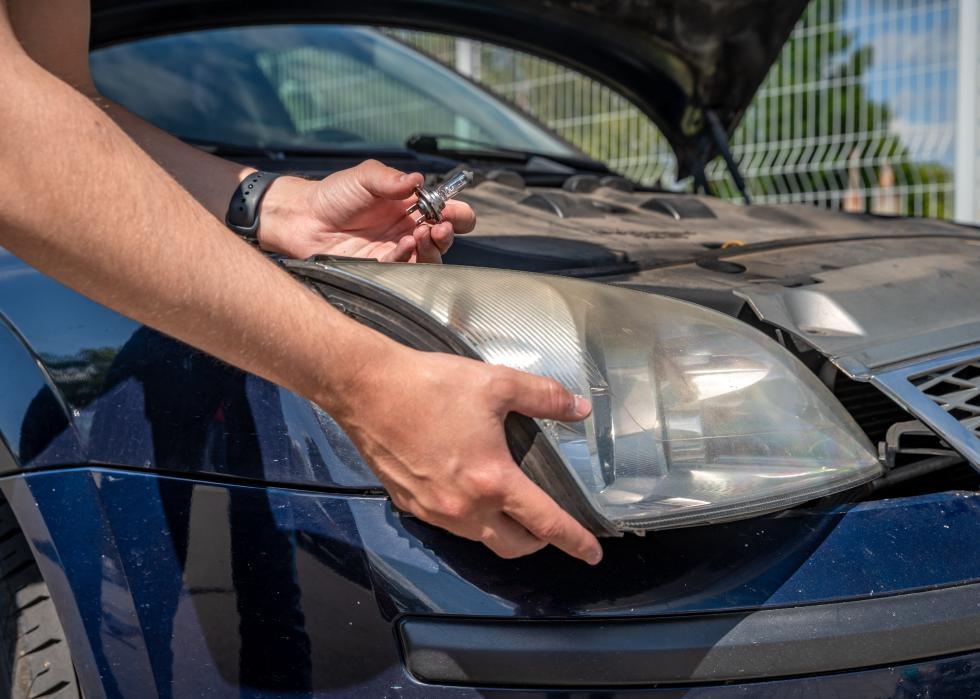 Man changing a car's headlight.