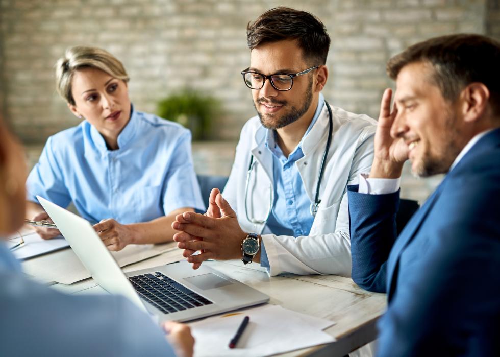 Group of healthcare workers and businessman using laptop in a meeting.