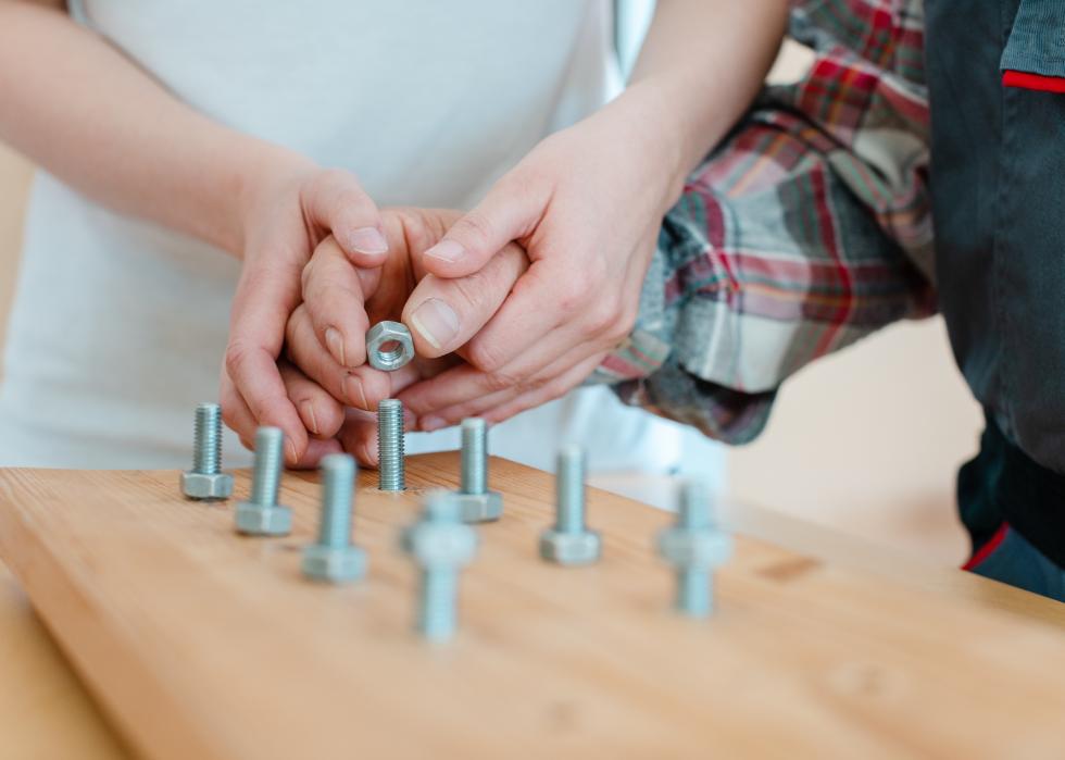Closeup of a hand in occupational therapy screwing a nut on a bolt.