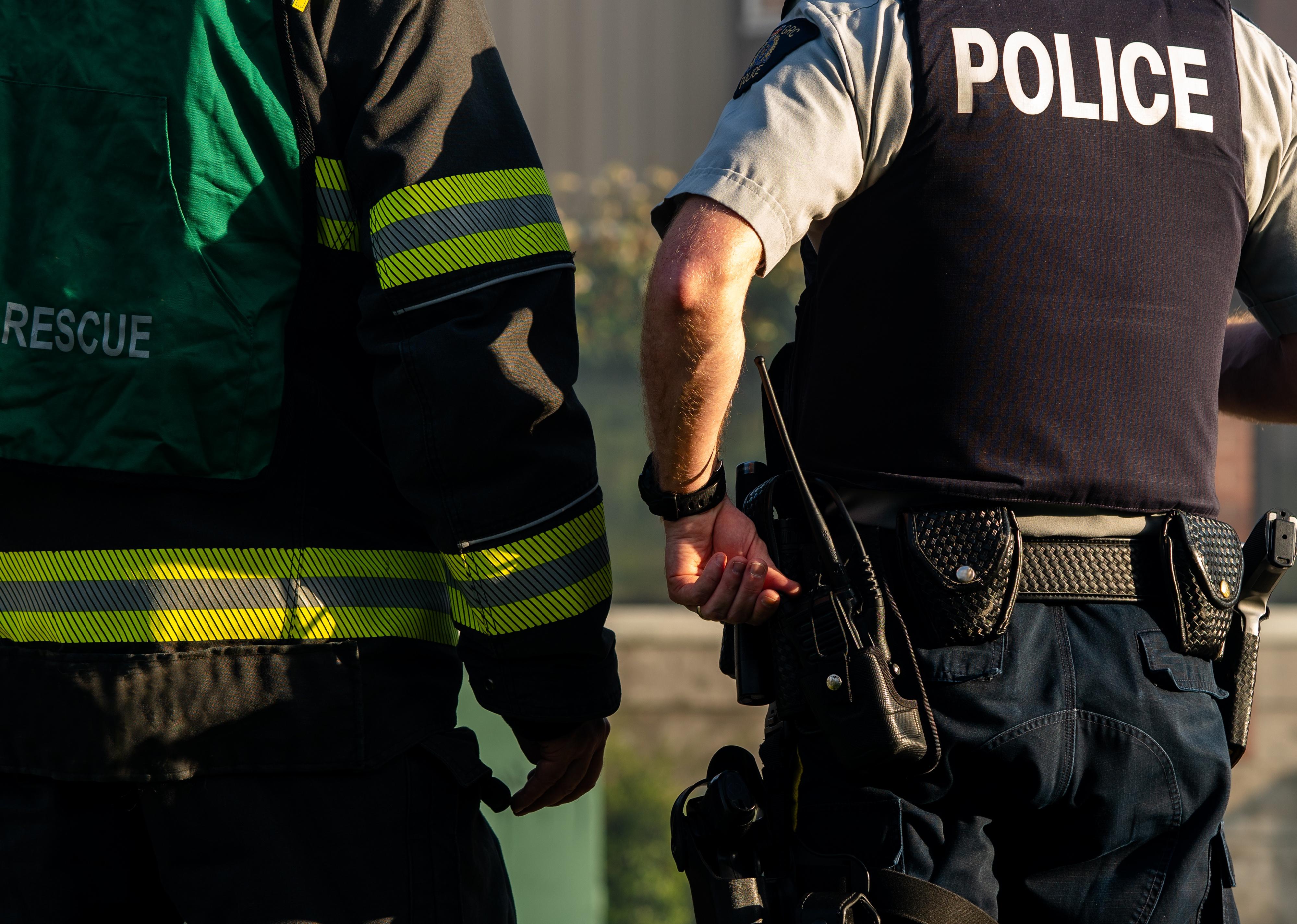 A firefighter and police officer standing one next to each other at a crime scene.