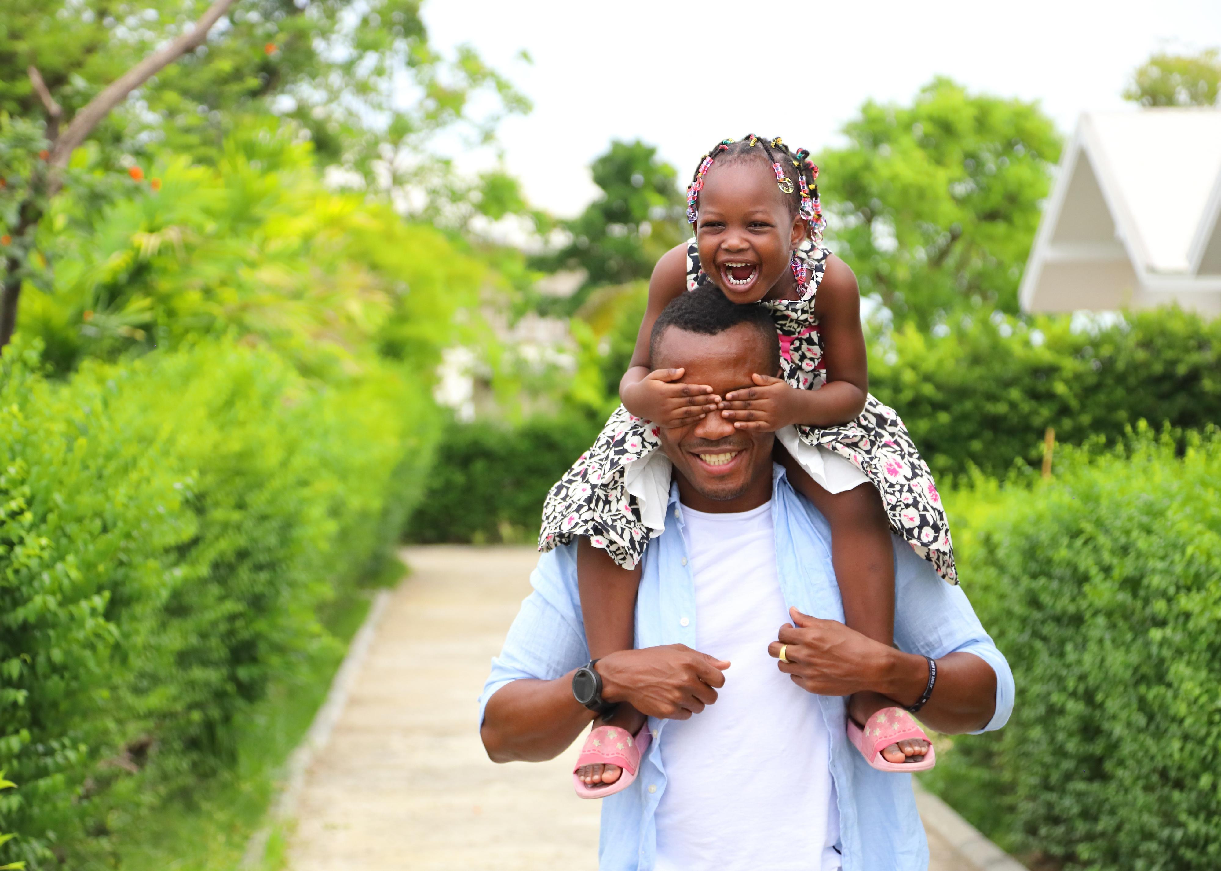 Father giving piggyback ride to his daughter while walking outside.