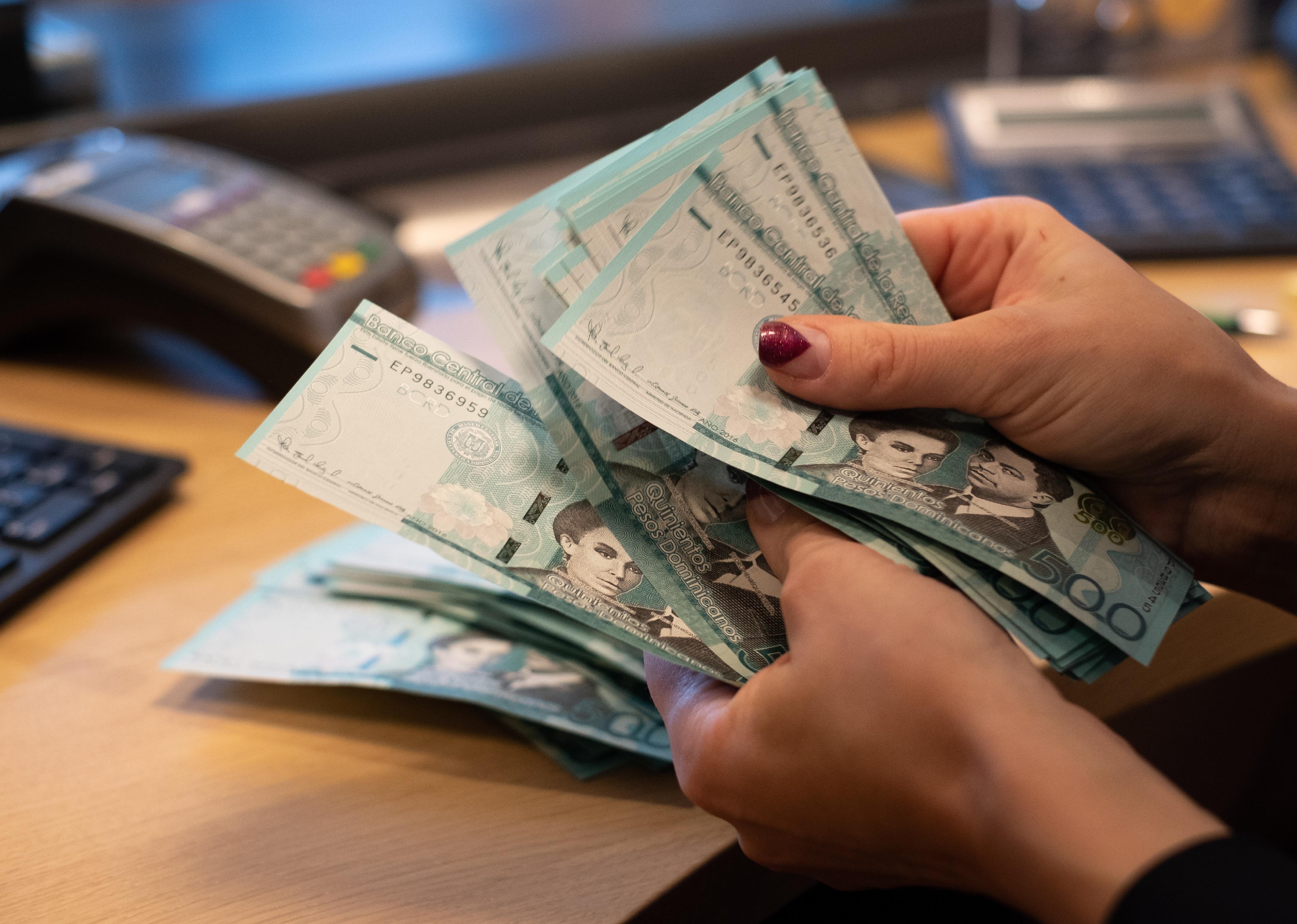 Cashier counting Dominican Republic 500 peso bank notes.