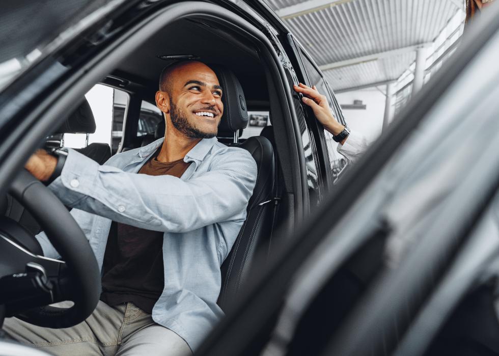 Young female salesperson showing a car to a male driver