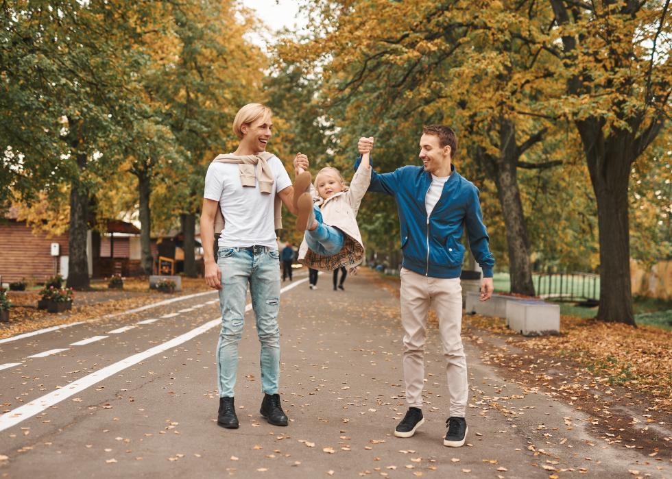 Couple in park swinging a little girl between them