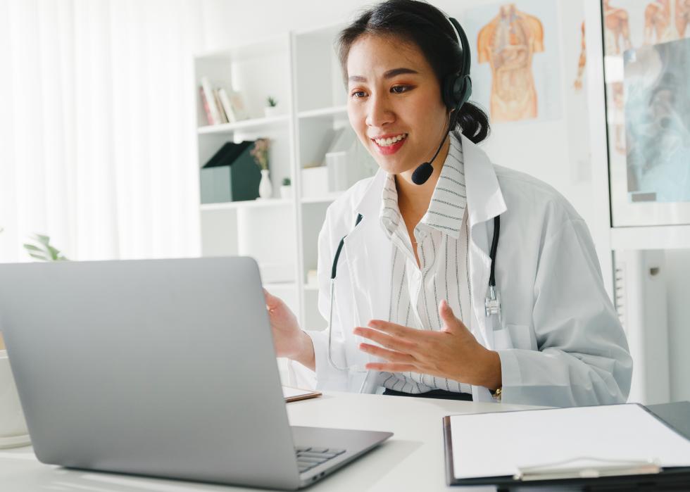 Young female doctor with stethoscope on video call with a patient
