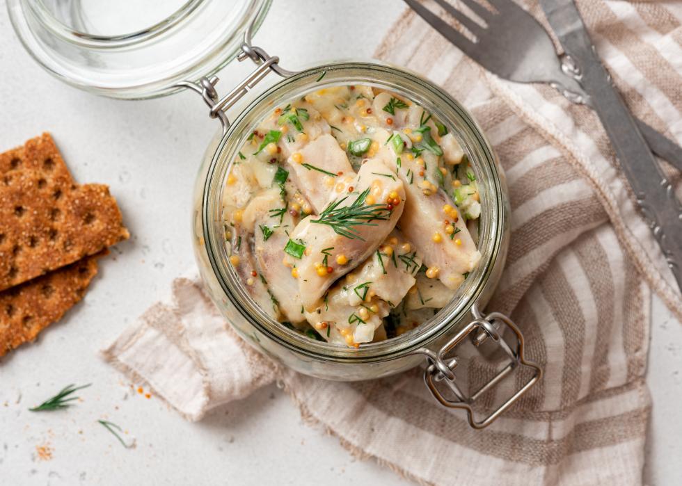 Pickled herring in a glass jar top view.