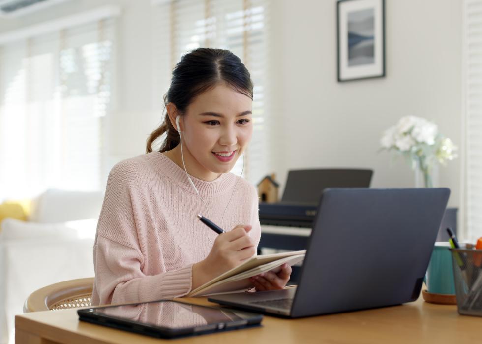 Asian female taking notes from laptop video call