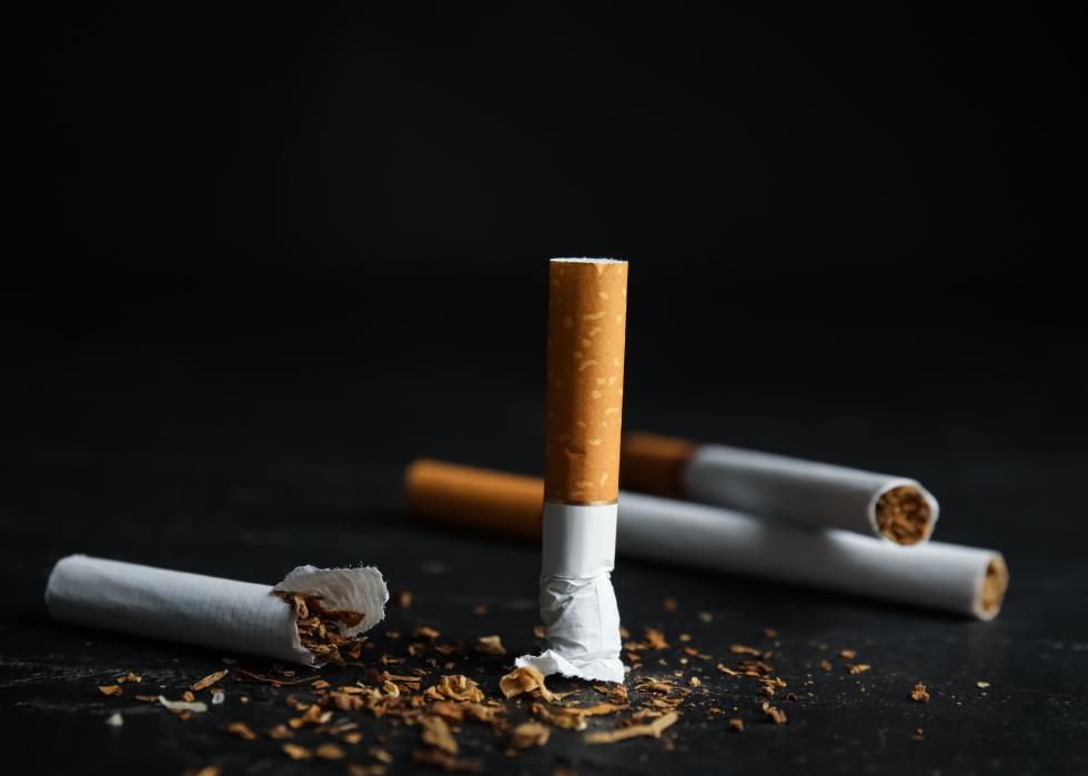 Broken and whole cigarettes on black table.