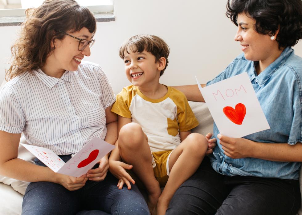 Boy with his two mothers holding greeting cards