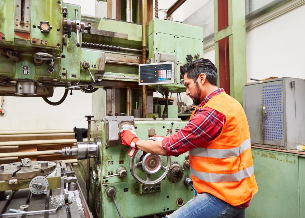 A male machinist operates a coordinate drilling machine
