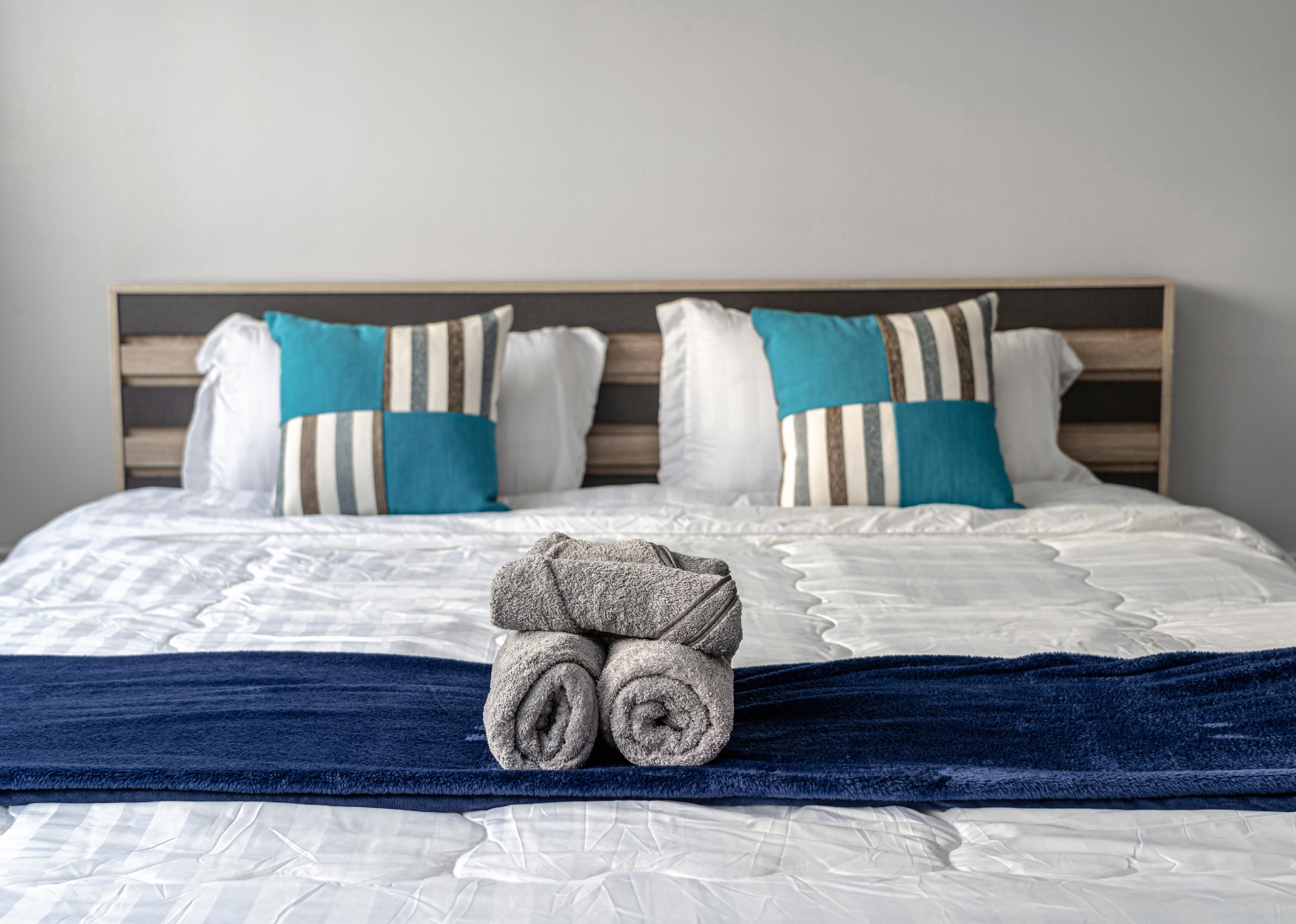 Close-up of rolled towels on queen-size bed.
