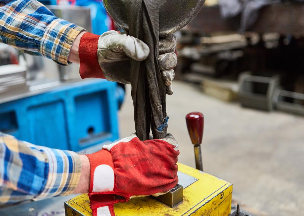 Close up of a worker with gloves attaching load to crane hook