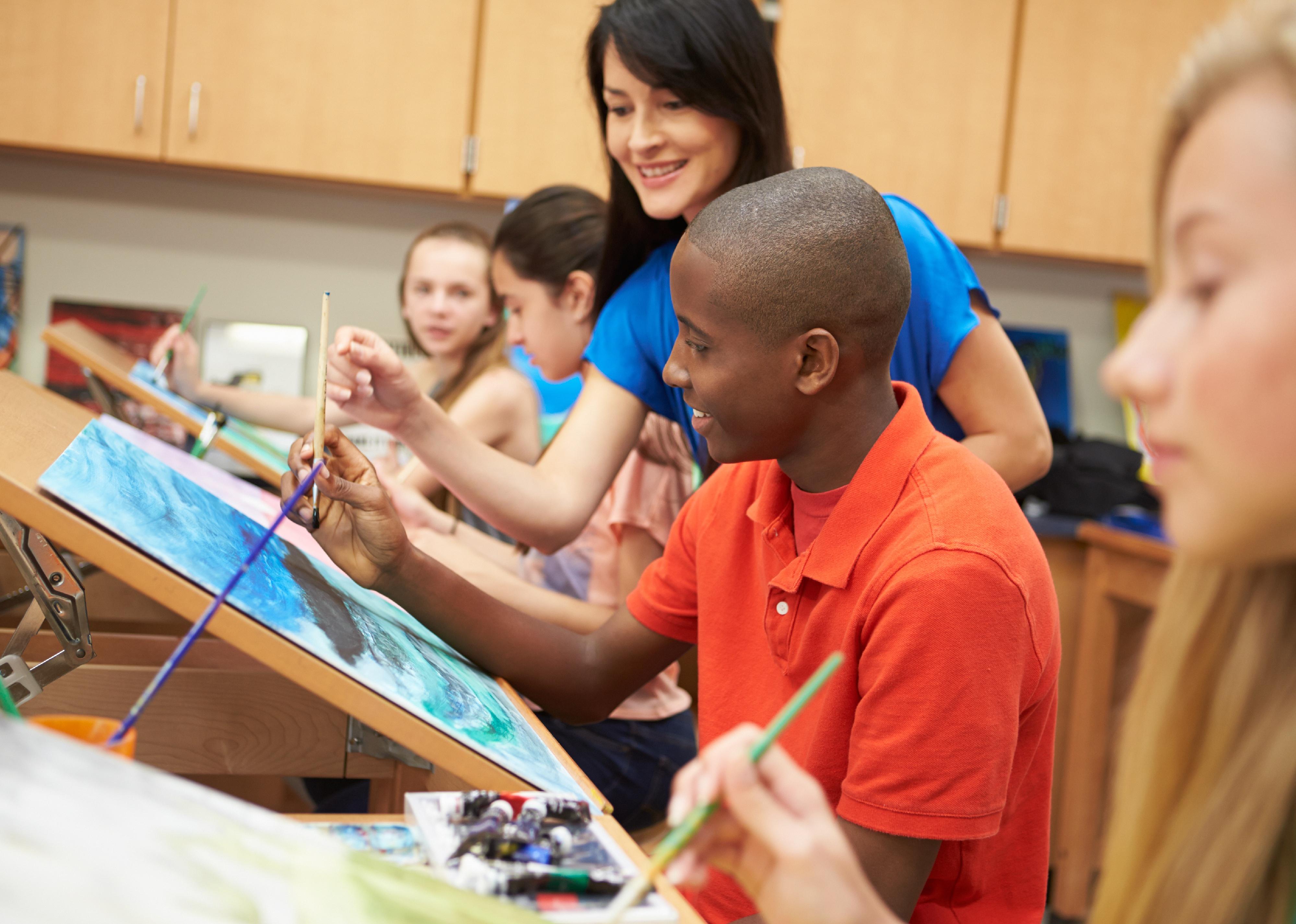 Art teacher helping student