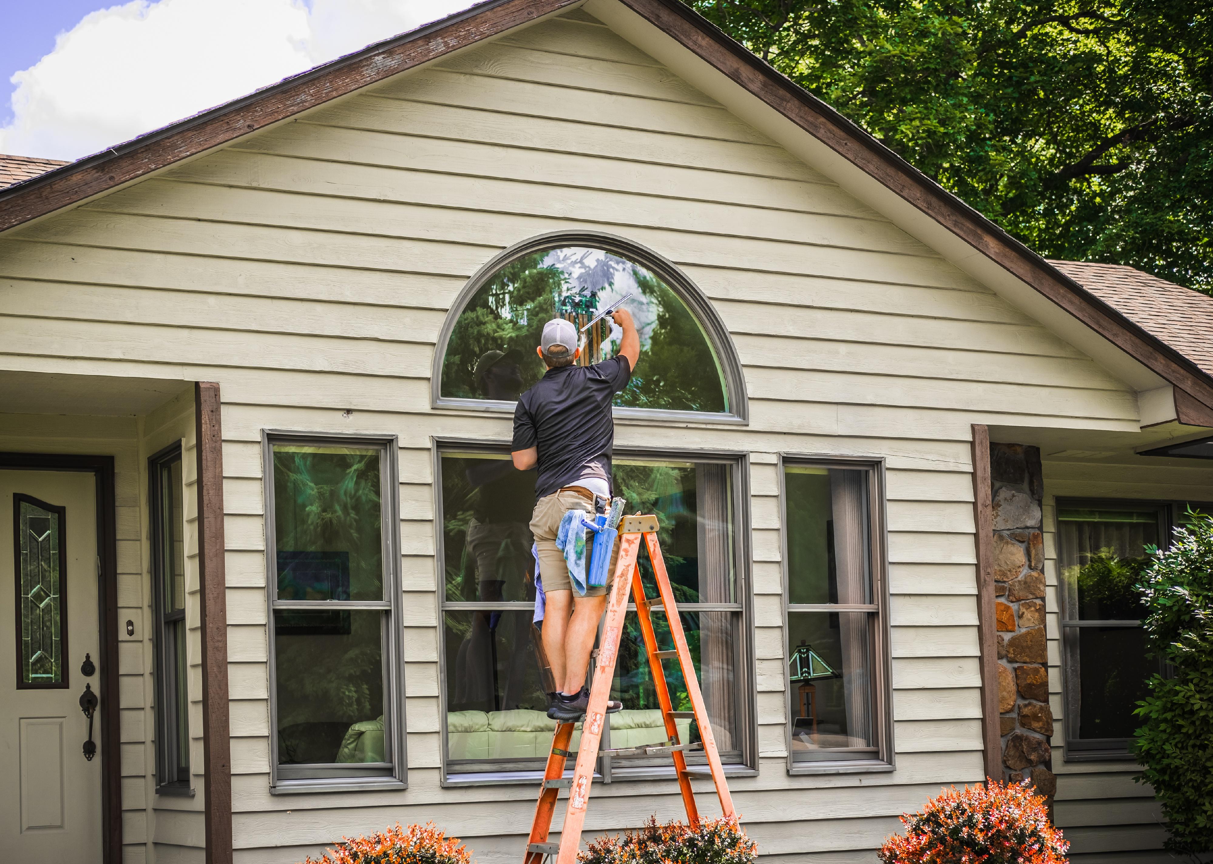 Window washer stands on ladder holding squeegee