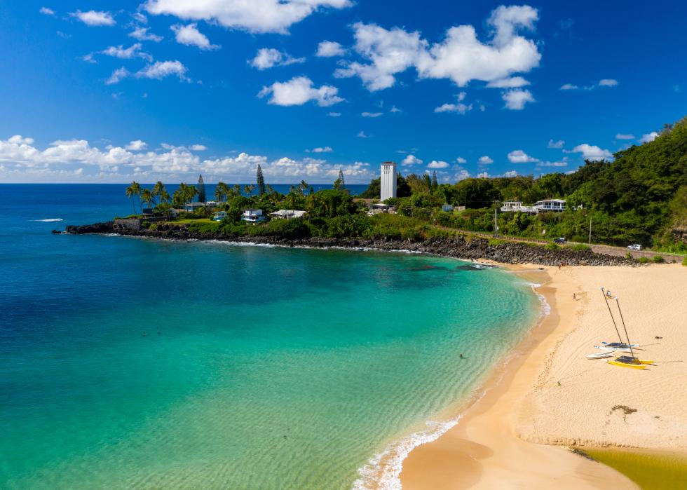 Waimea Bay beach with boats and clear sky.