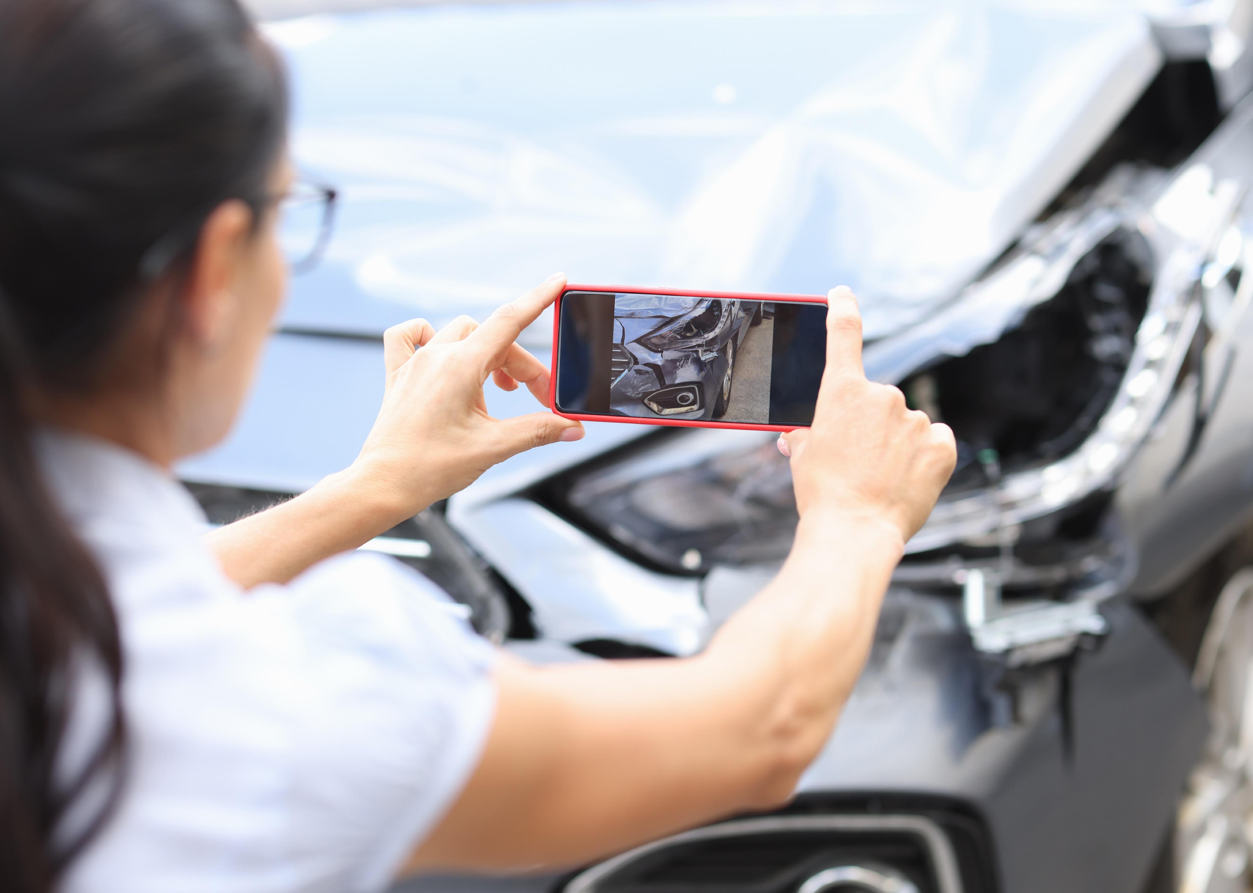 Agent takes pictures of damage to car after accident 