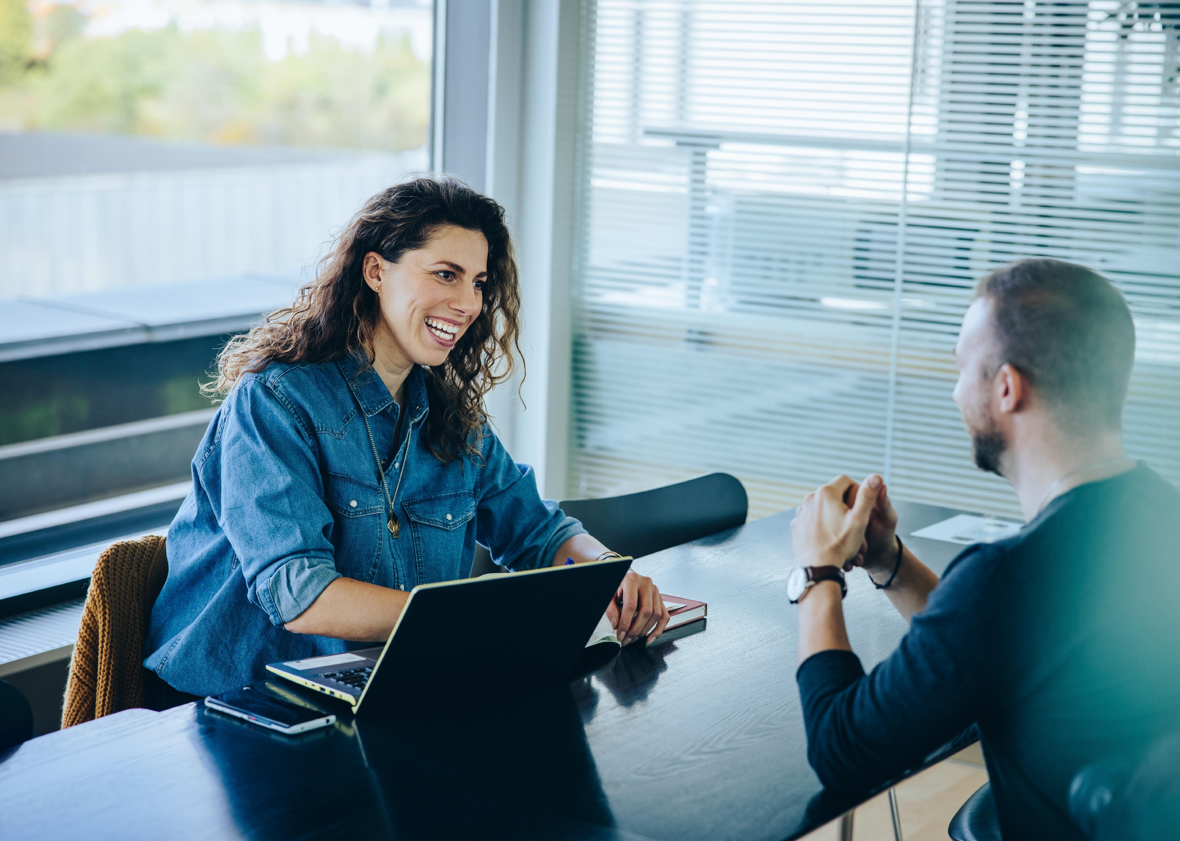 Manager interviewing young man in office boardroom