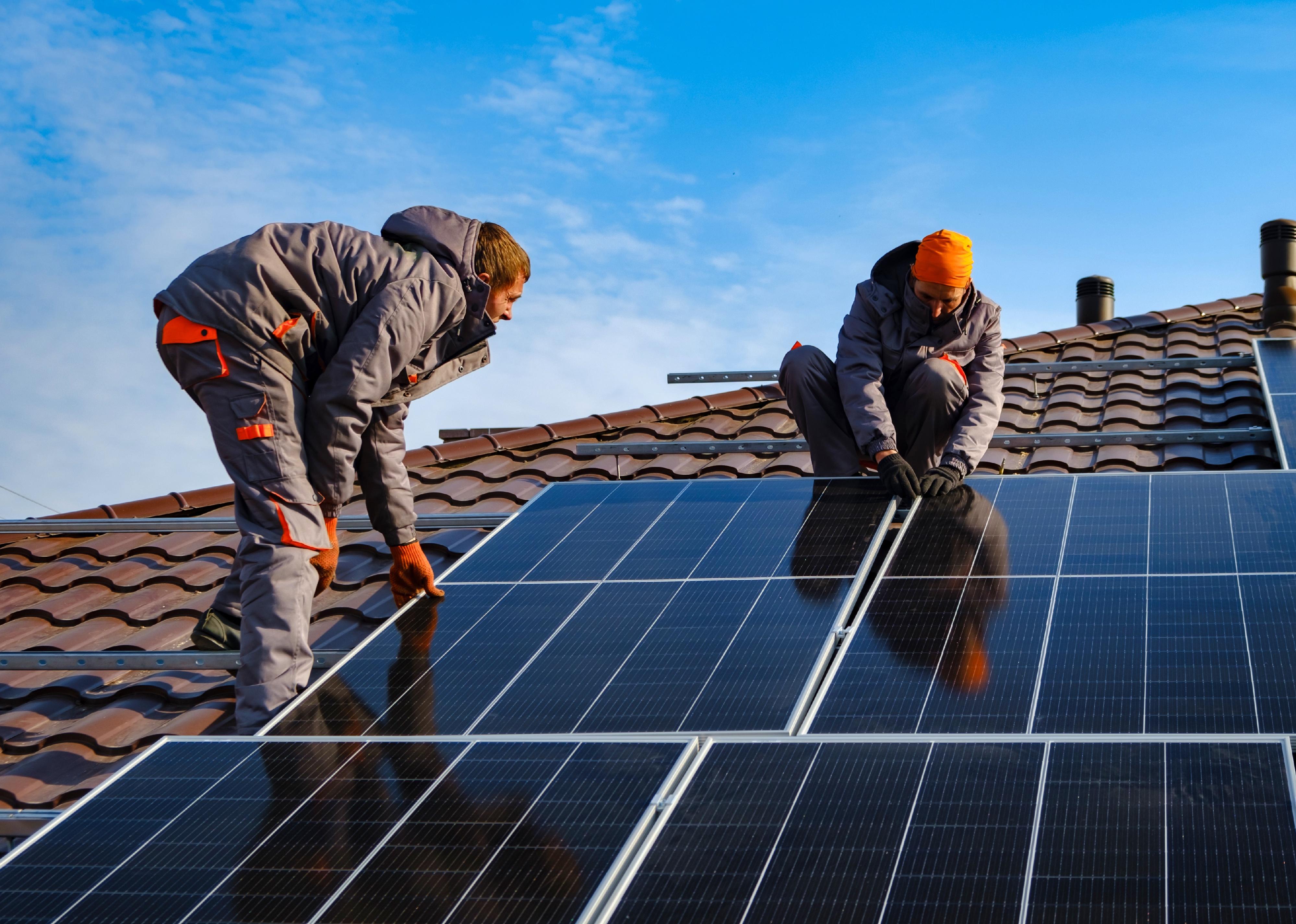 Workers installing solar panels on roof.