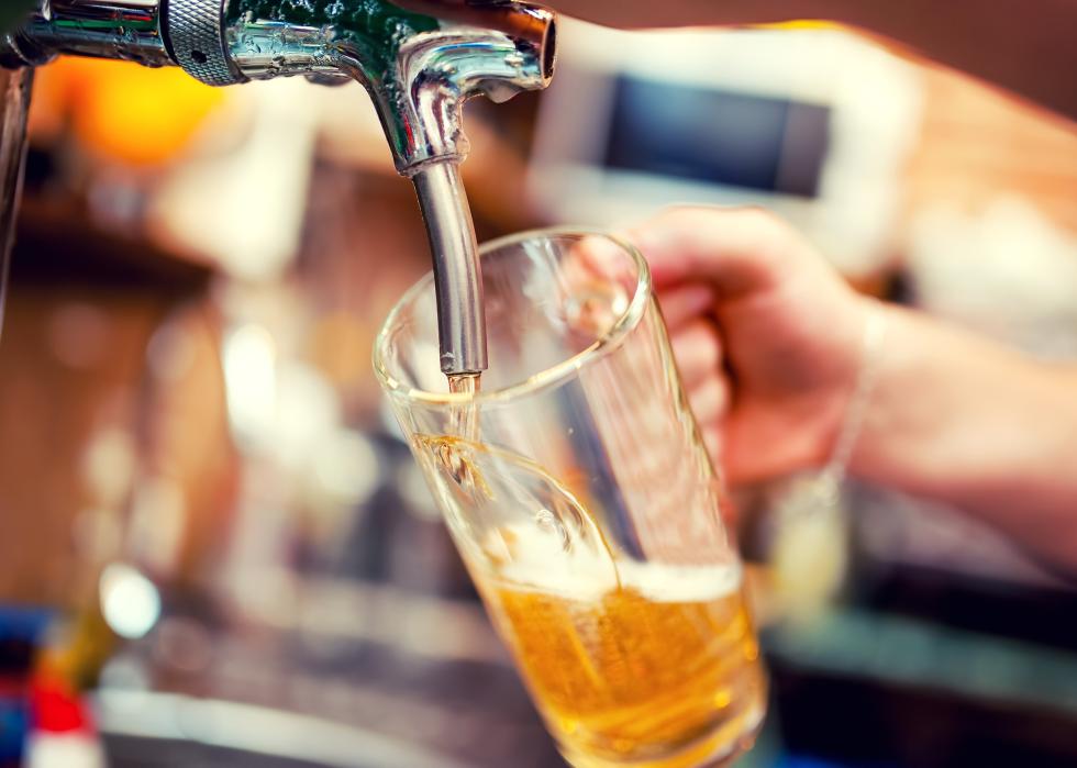 Close-up of barman hand at beer tap pouring a draught lager beer