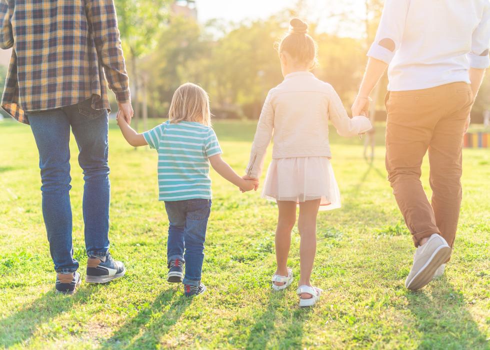 Two children walking hand in hand with their dads