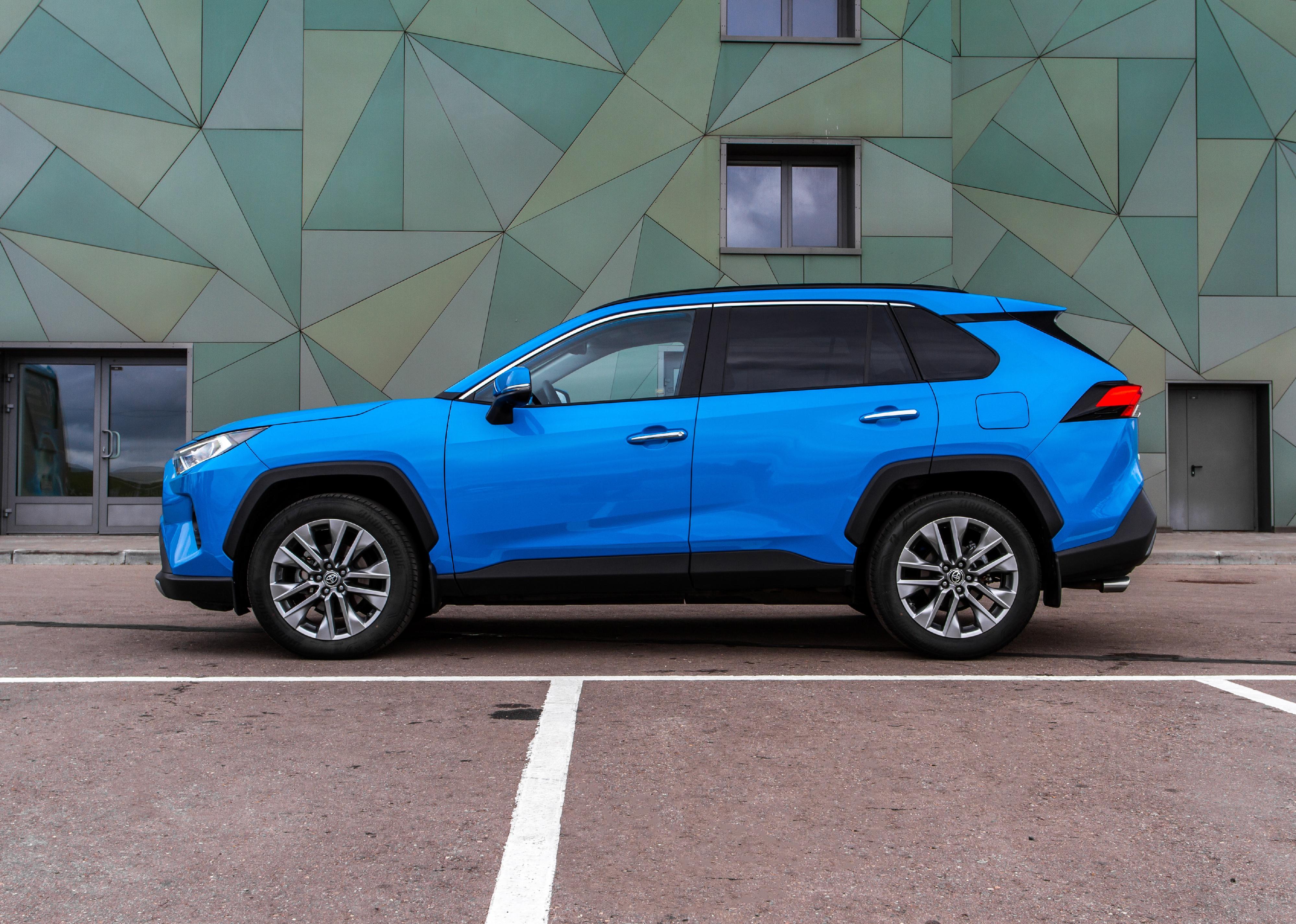 Blue Toyota RAV4 on city background.