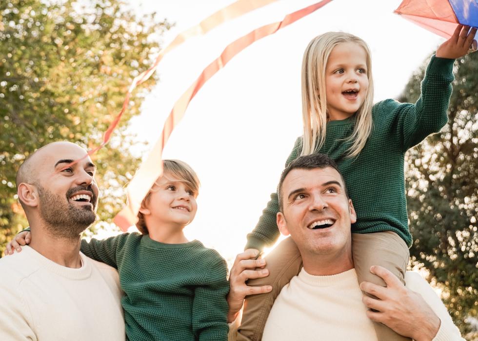 Male couple with children having fun with kite toy