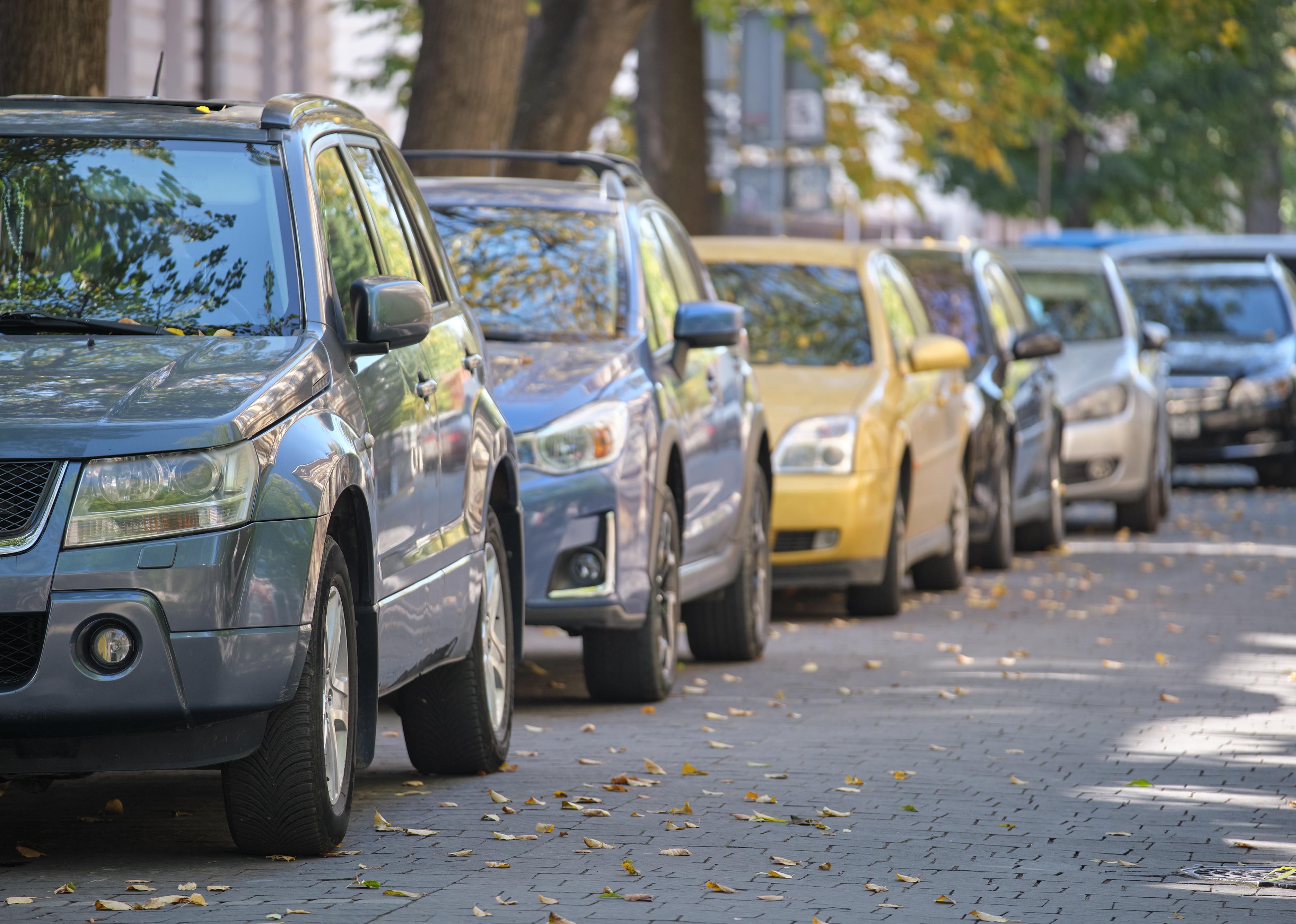 City traffic with many cars parked in line on street side.