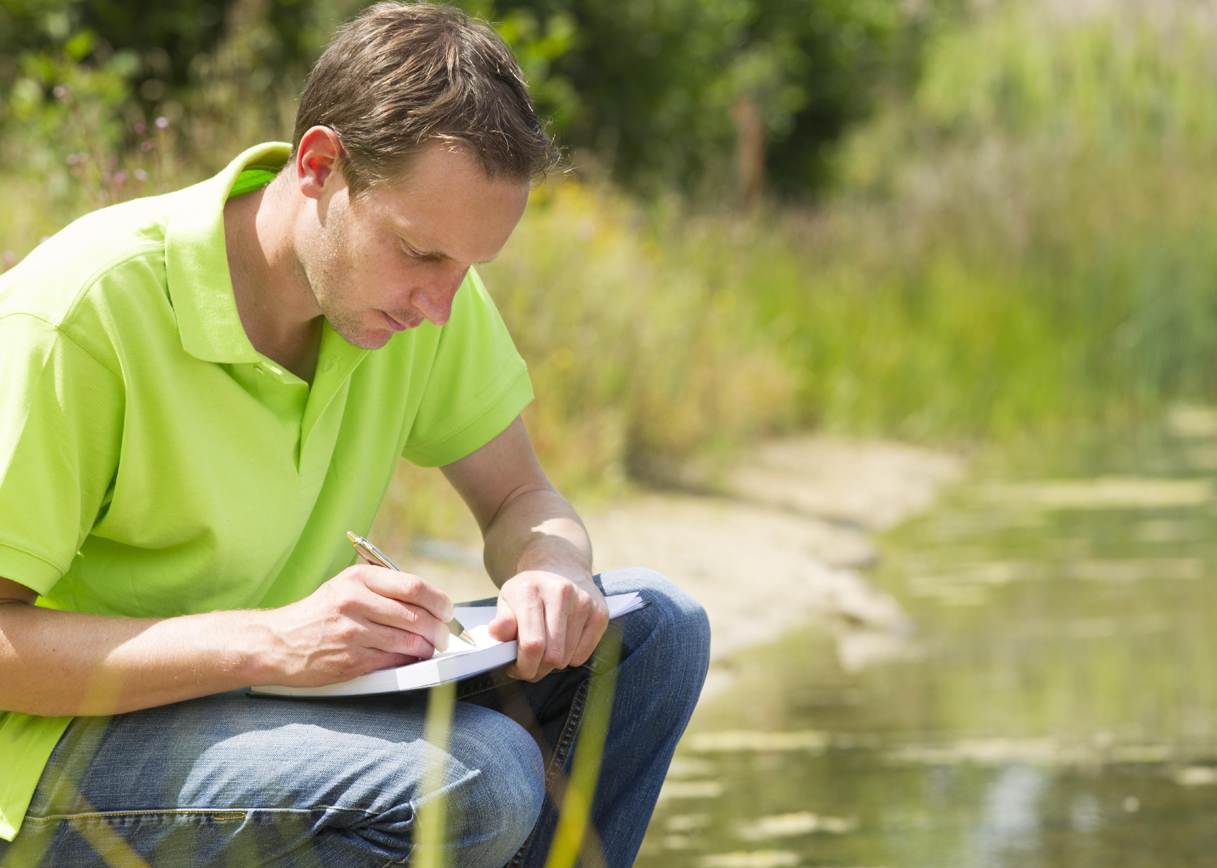 A hydrologic technician writes in a notebook.