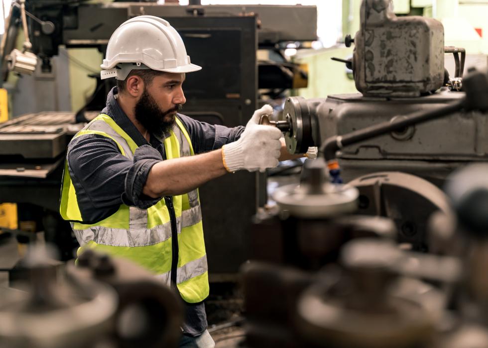 Factory worker in safety equipment operating machinery