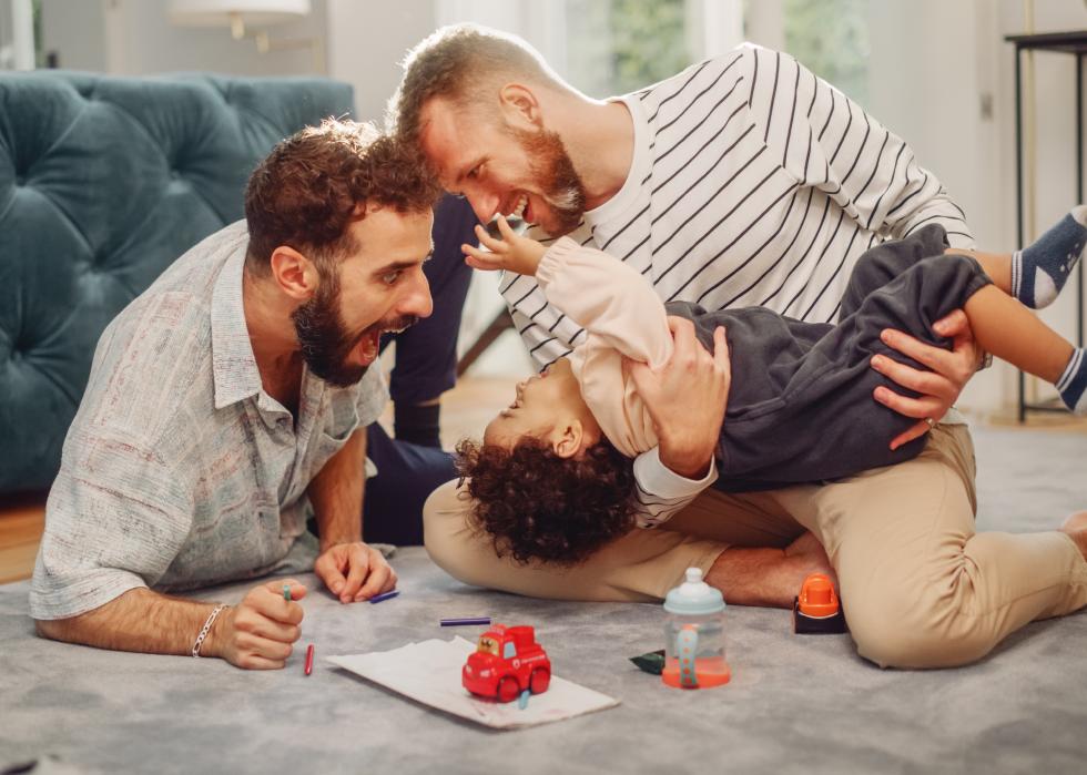 Two men playing with little boy on floor