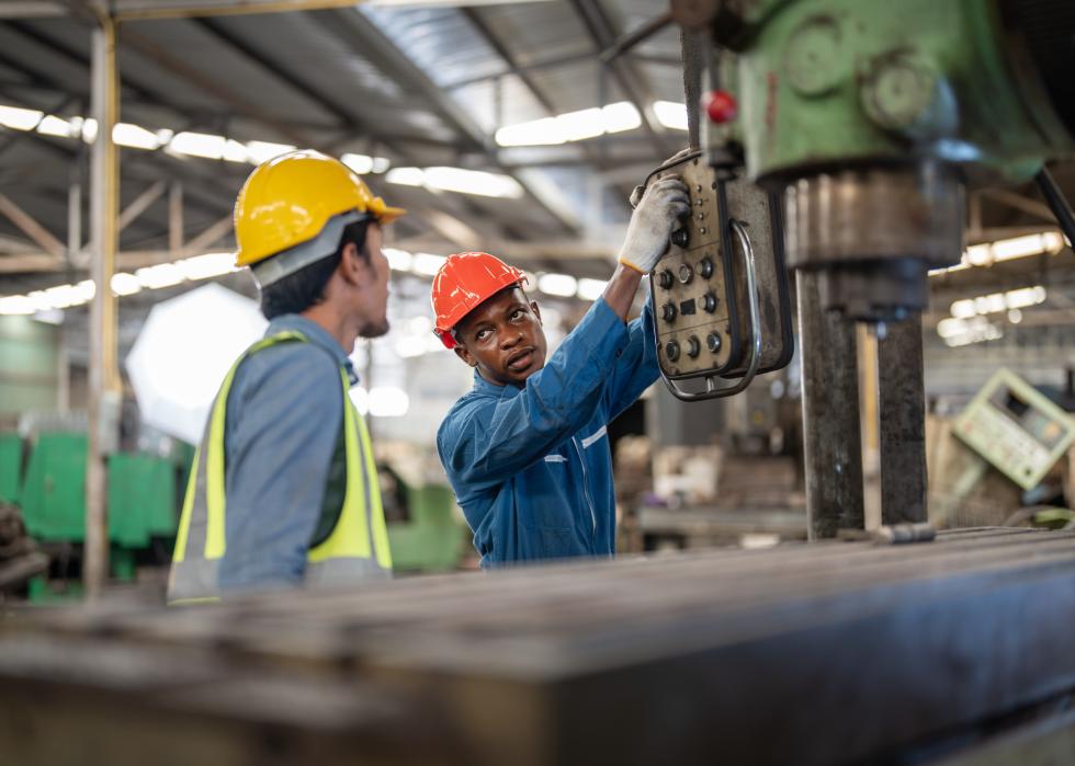 Two men working at steel heavy machine in a factory