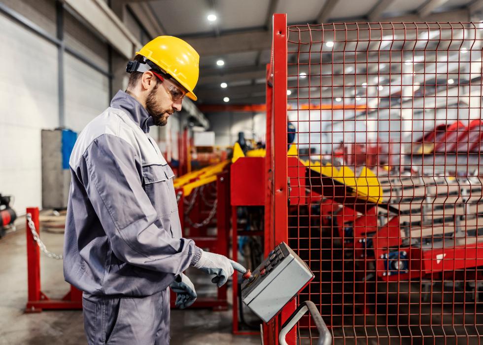 Worker pressing buttons on a console in a steel factory